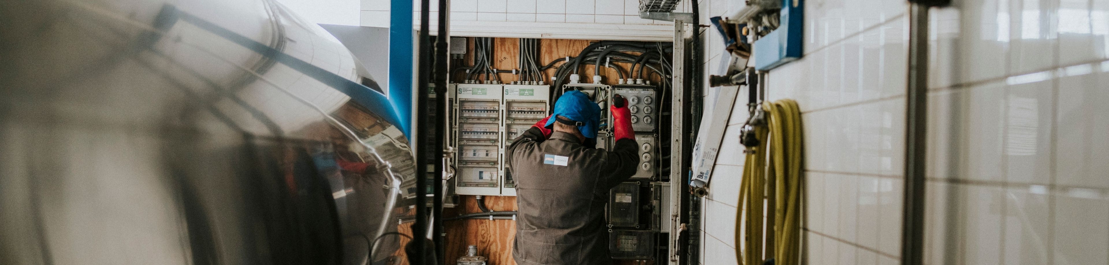 Een installateur verricht werkzaamheden in de meterkast van een bedrijf.