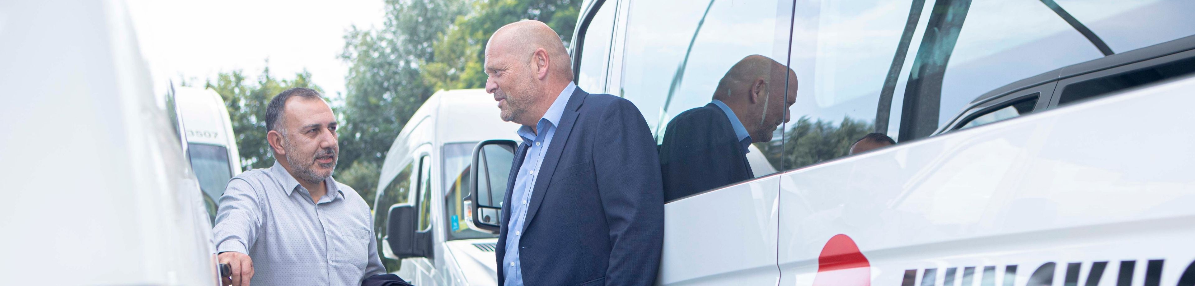 2 mannen in overleg staand tegen taxi van Munckhof