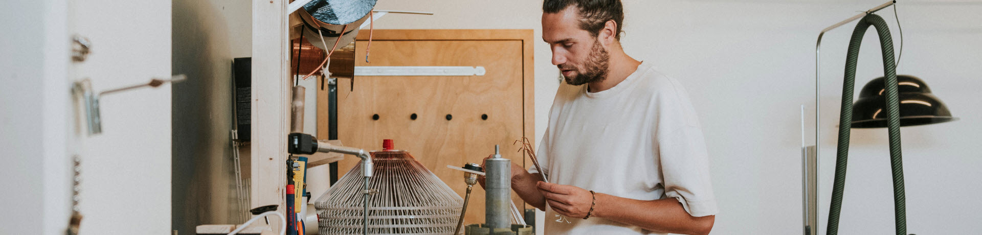 Een man met een wit t-shirt staat in een creatieve werkplaats.