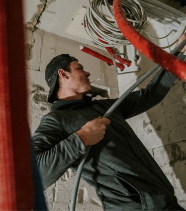 Een man is op een bouwlocatie bezig met het plaatsen van leidingwerk.