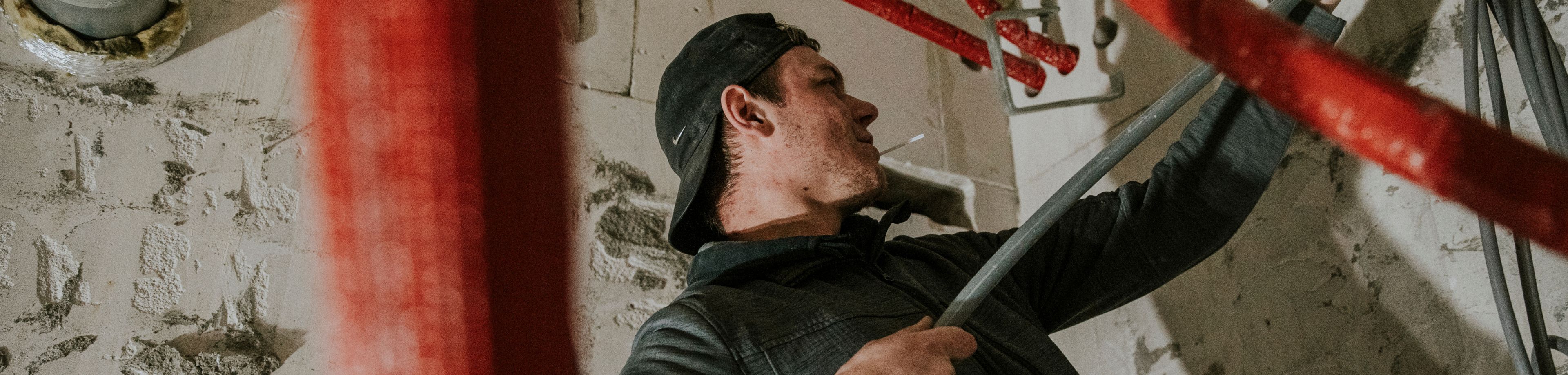 Een man is op een bouwlocatie bezig met het plaatsen van leidingwerk.