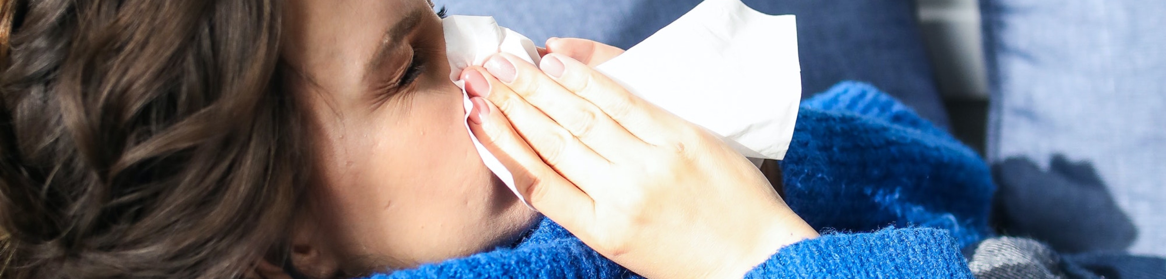 Een vrouw die haar neus snuit in een papieren zakdoekje