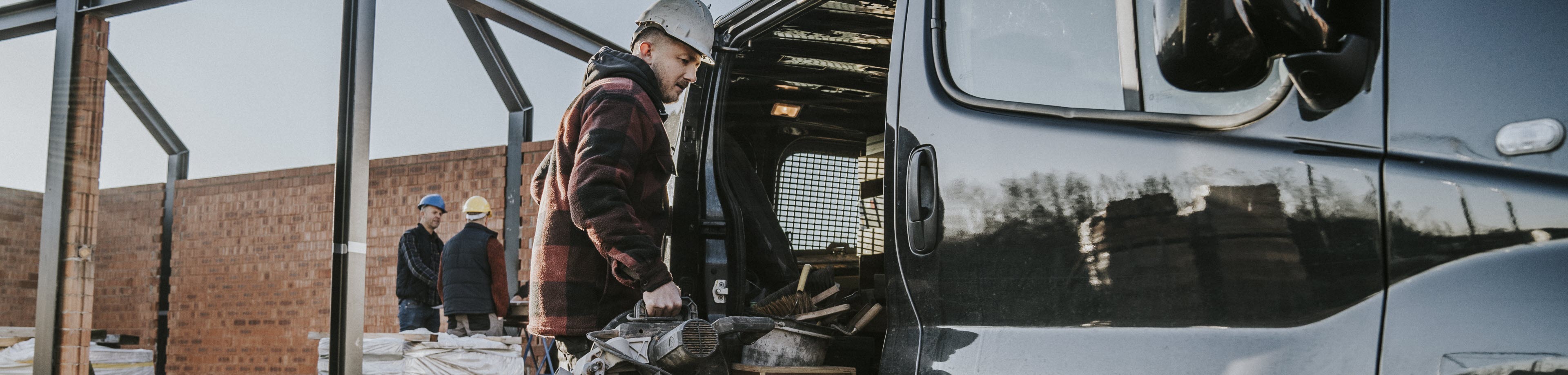 Een foto van een man die gereedschap in een zwarte werkbus legt.