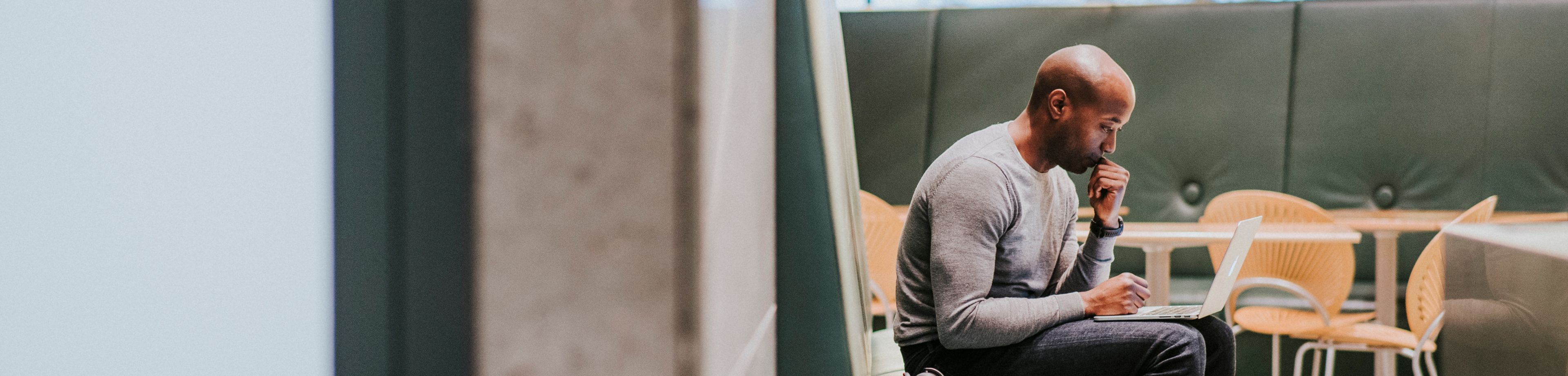 Man zit met laptop op schoot na te denken