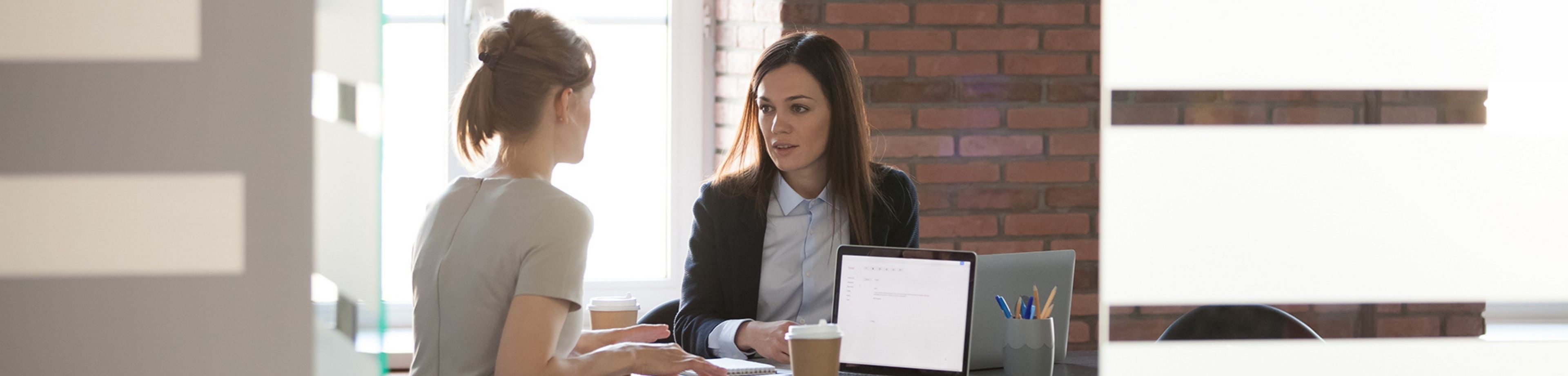 Twee vrouwen achter de laptop in overleg met elkaar
