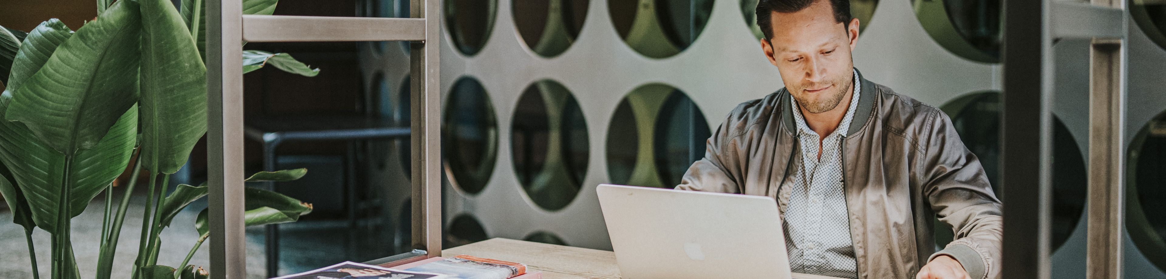 Een man werkt in een industriële kantooromgeving op zijn laptop.