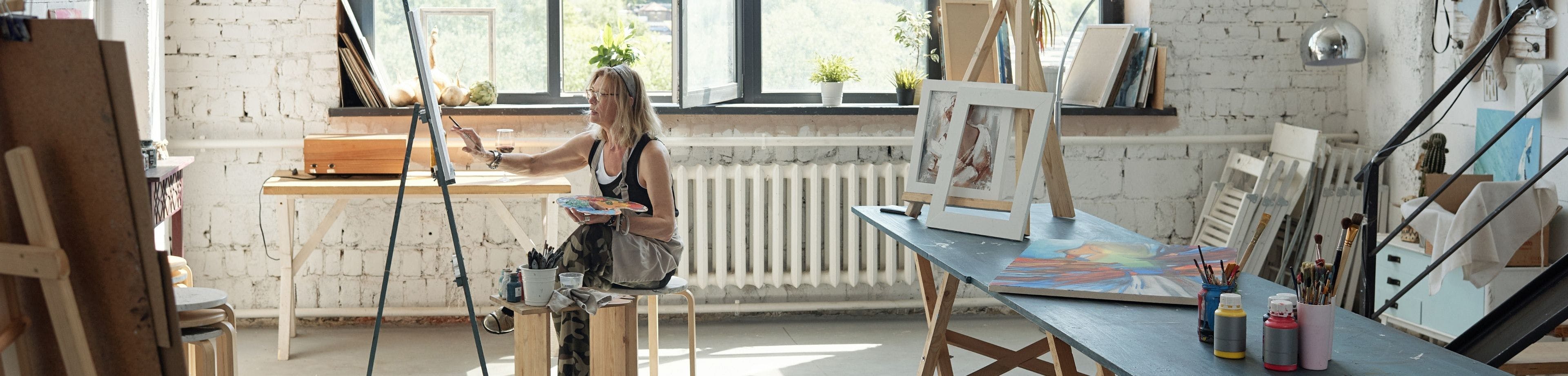Vrouw zit te schilderen in een grote, lichte ruimte