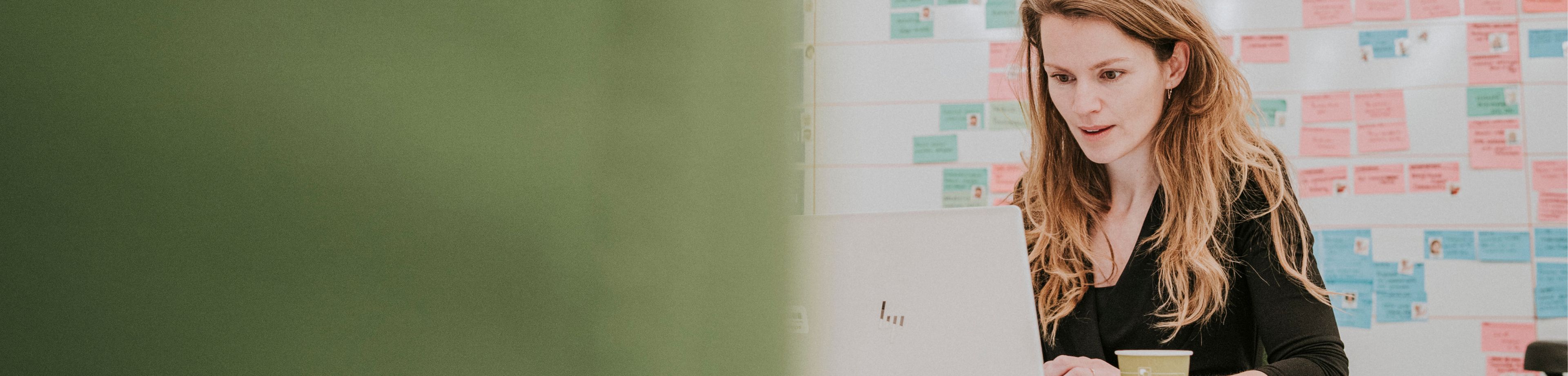 Een vrouw werkt in een kantooromgeving op haar laptop.