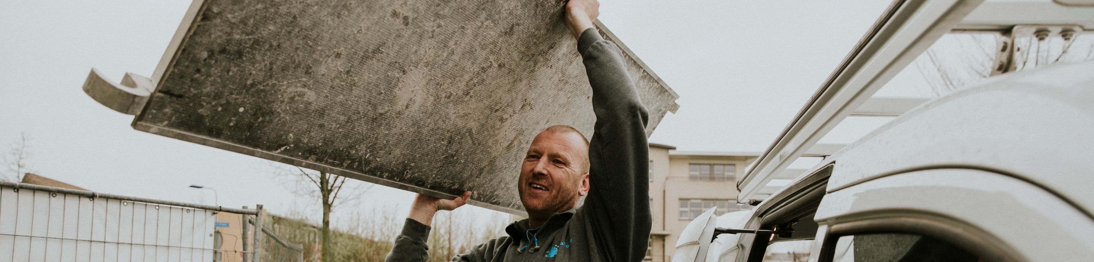 Een man tilt een onderdeel van een rolsteiger uit zijn bedrijfsauto.