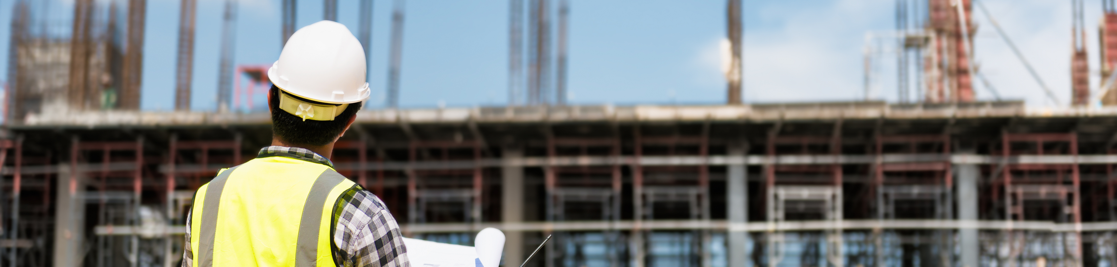 Bouwopzichter kijkt naar gebouw in aanbouw