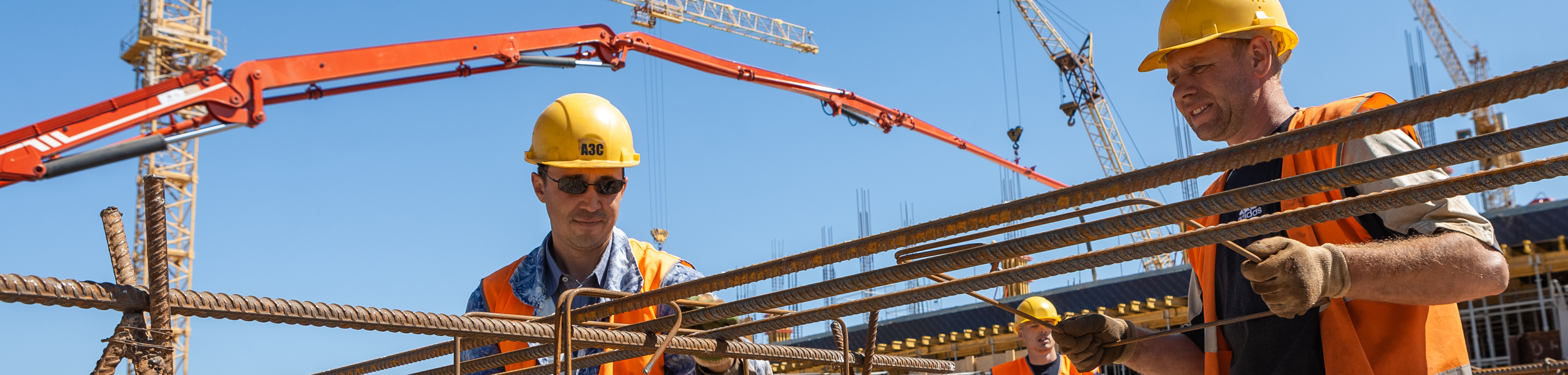 Mannen met helm op en veiligheidshestje aan, aan het werk op de bouw