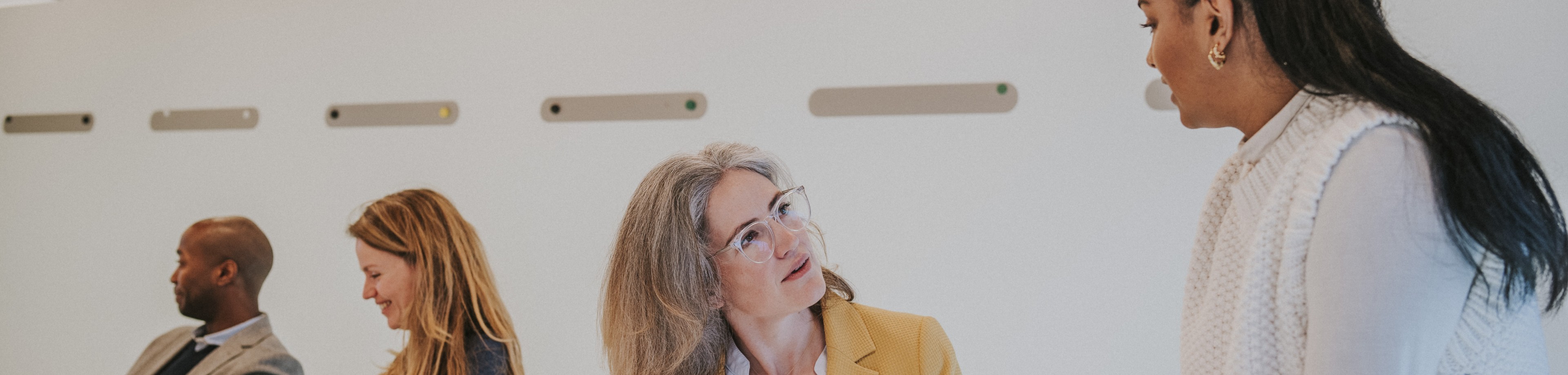 4 collega's zitten in een vergaderruimte en zijn in gesprek met elkaar.