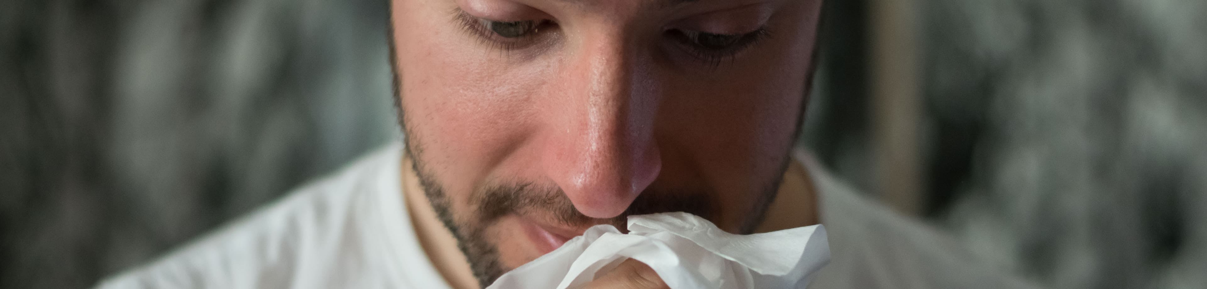 Een man veegt zijn neus af aan een zakdoek