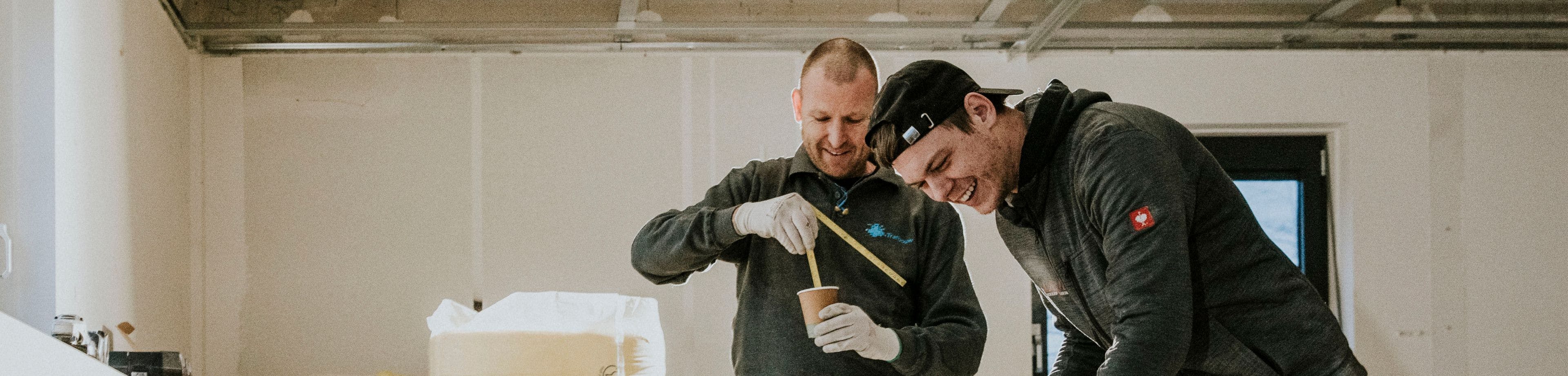 2 jonge mannen lachen en drinken koffie op de bouw.