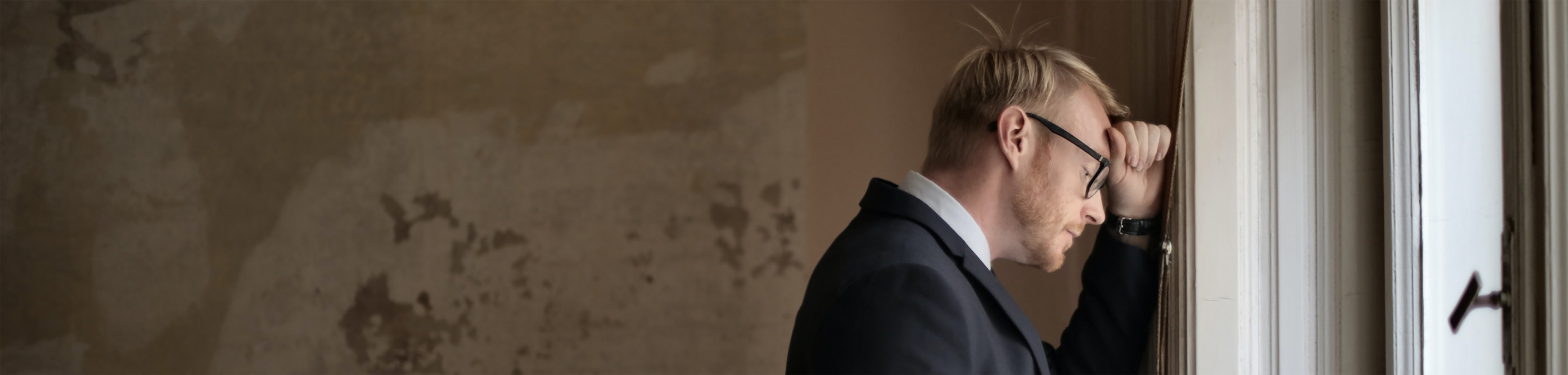 Een ondernemer die met zijn voorhoofd tegen een muur staat en aan het nadenken is