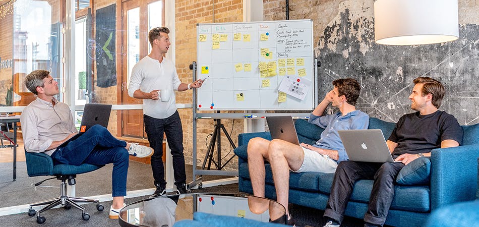 4 ondernemers die samen aan het brainstormen zijn bij een whiteboard met post-its