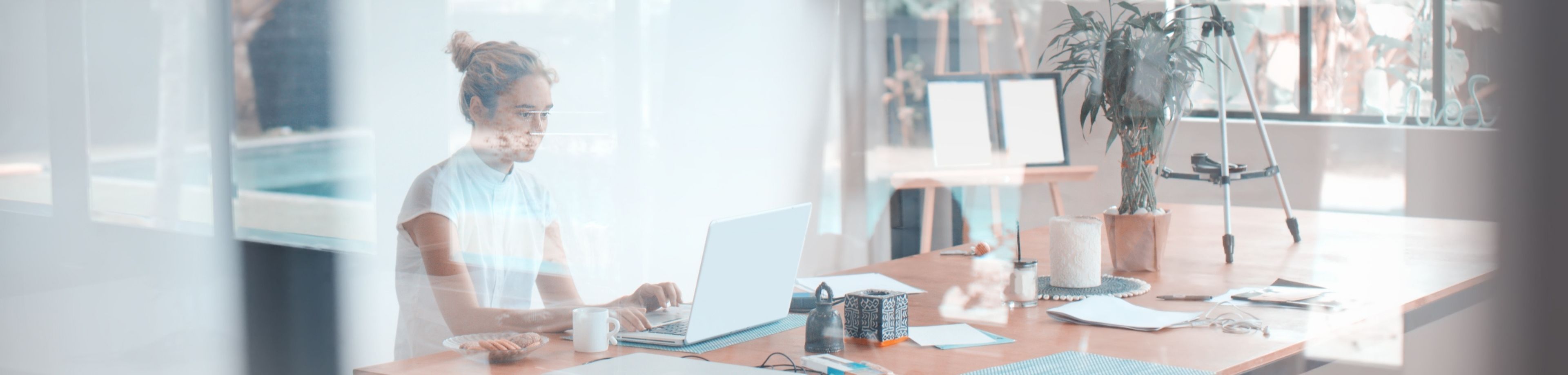 Vrouw werkt thuis achter een laptop, gezien door een raam