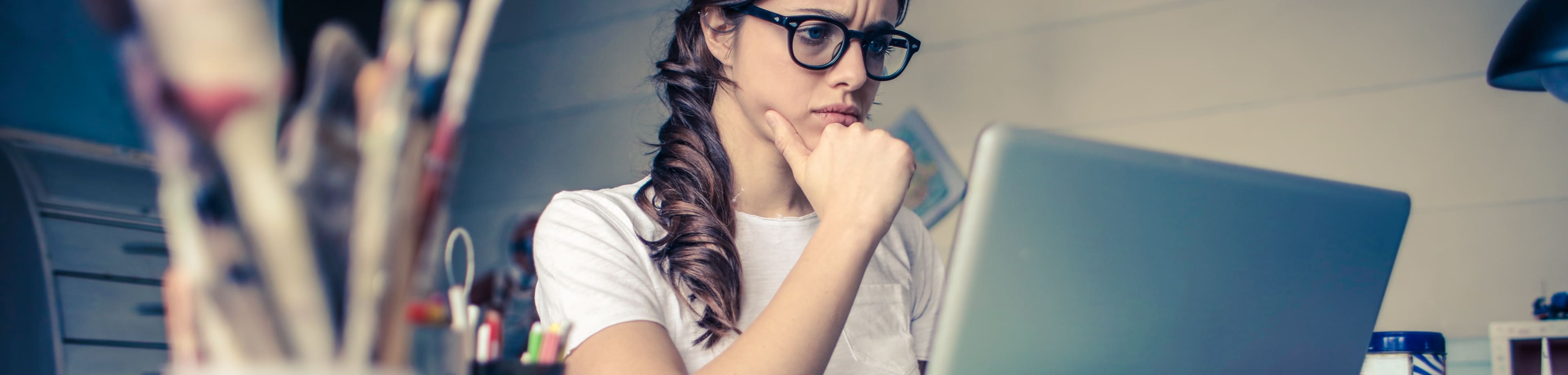 Vrouw die fronsend naar haar laptopscherm kijkt