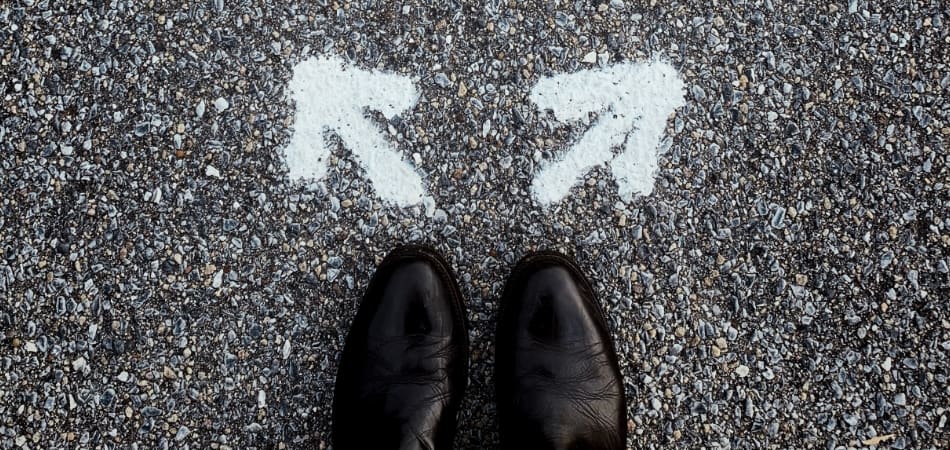 Een paar schoenen op het asfalt, met twee witte pijlen die naar links en rechts wijzen