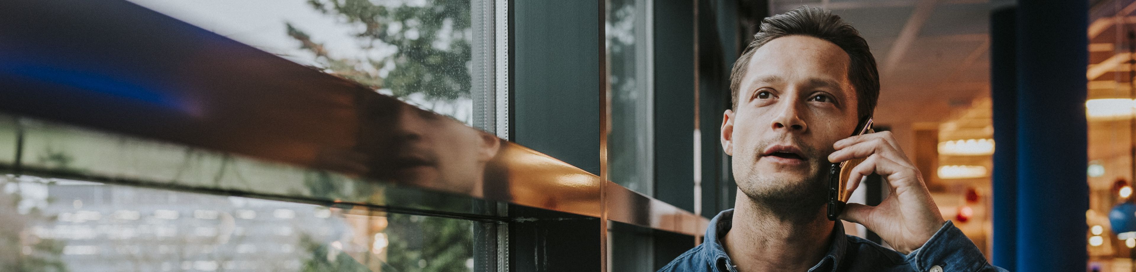 Man staat bij het raam en is aan het bellen