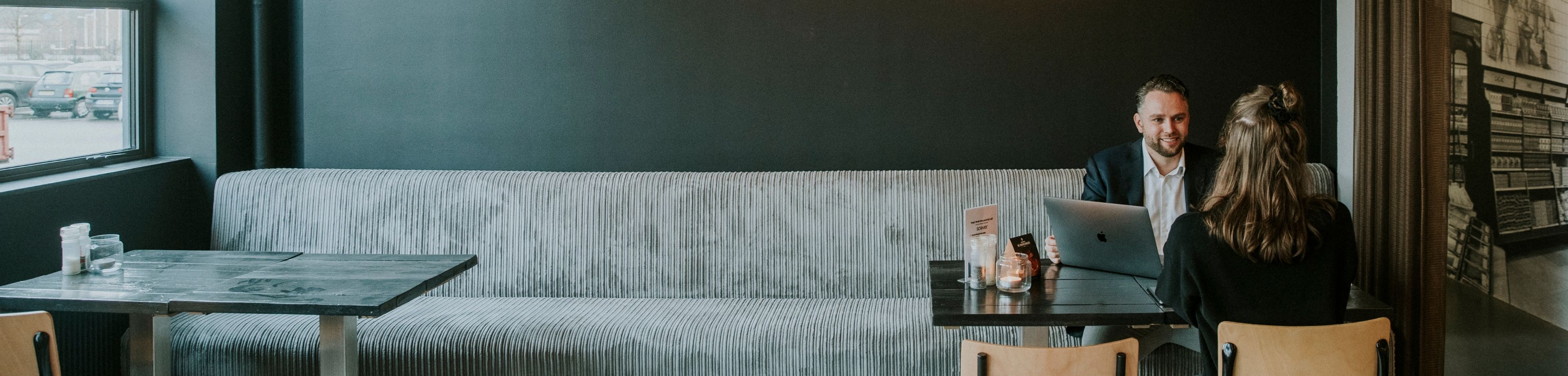 2 mensen zitten aan een tafel en zijn in gesprek met elkaar