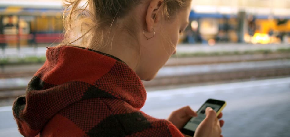 Vrouw die naar een mobiel in haar handen kijkt