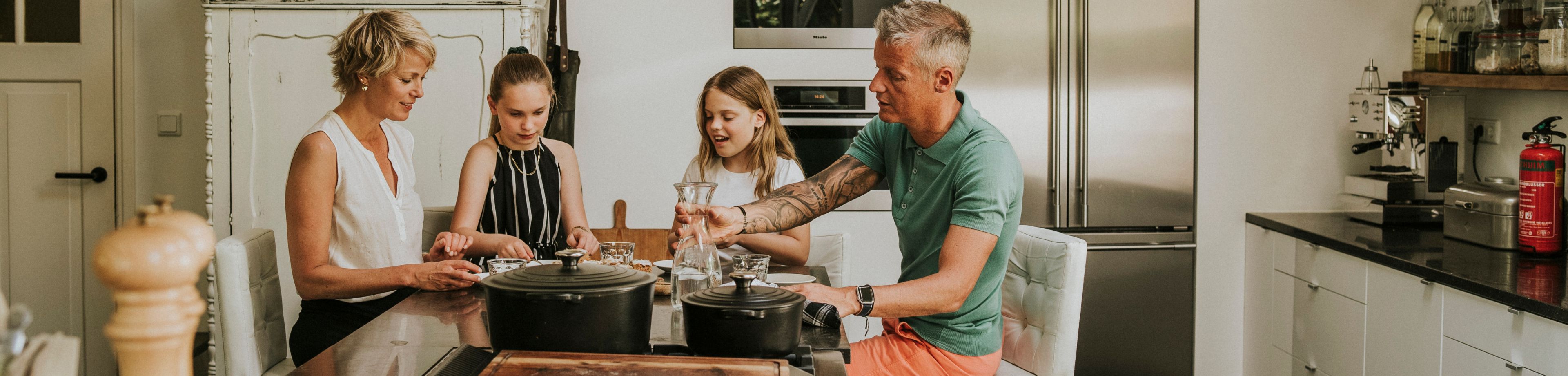 Een gezin zit in de keuken aan tafel bij het fornuis te eten