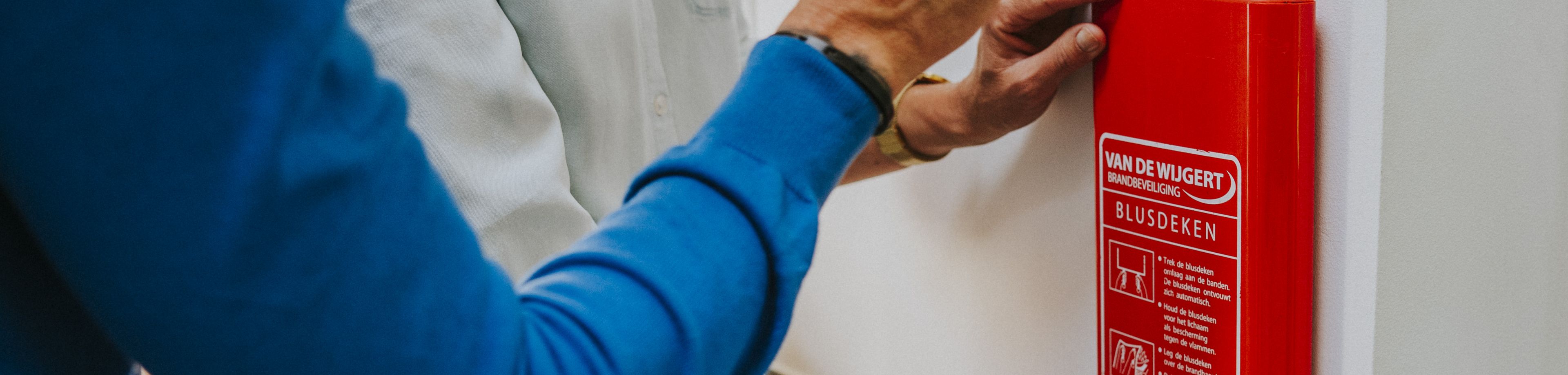 2 mensen hangen een brandblusdeken op.