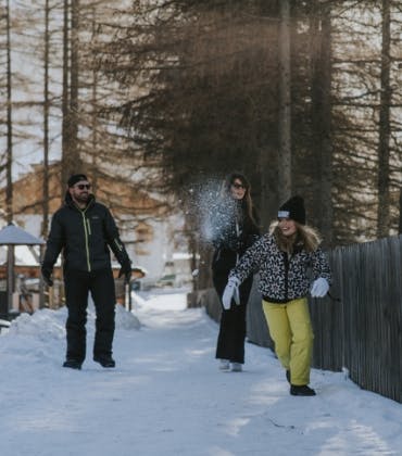 Een man, vrouw en kind maken door de sneeuw een wandeling in het bos.