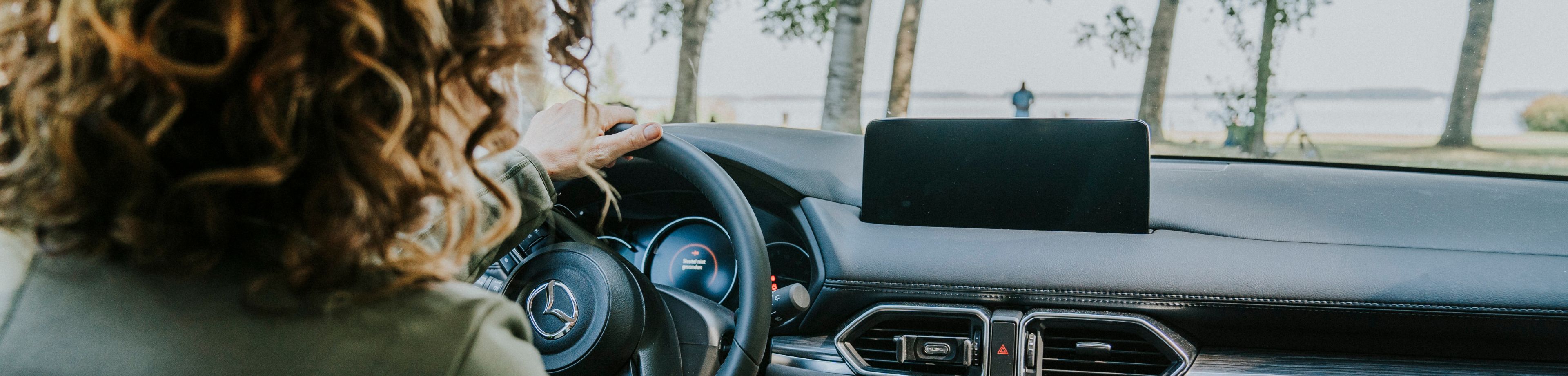 Vrouw zit in auto en start de auto