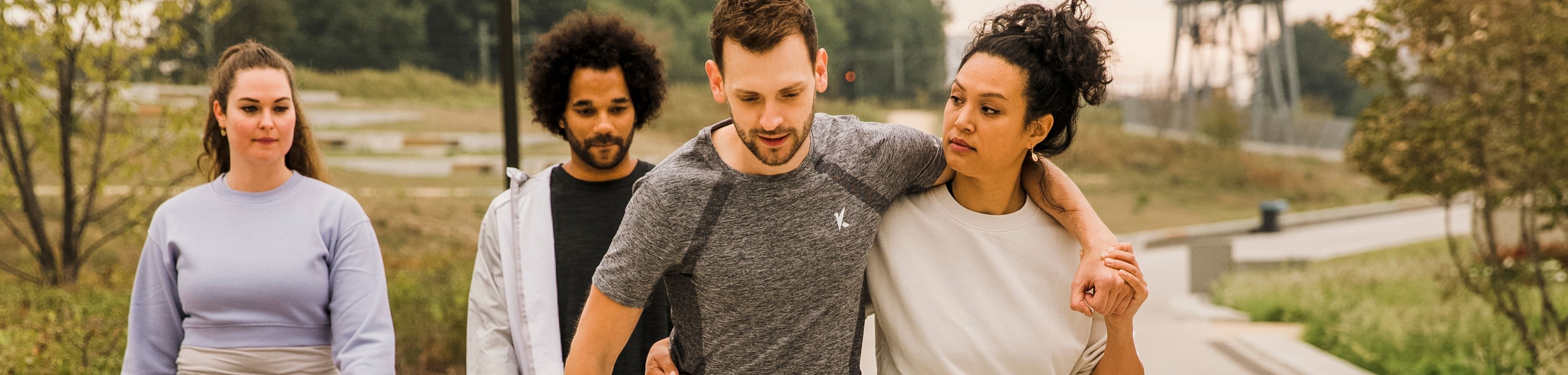 Een groepje van 4 mensen loopt in sportieve kleding door een park.