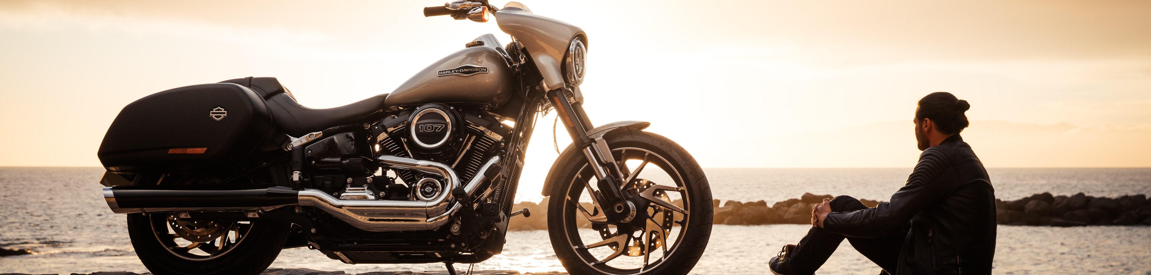 Man zittend naast zijn geparkeerde motor