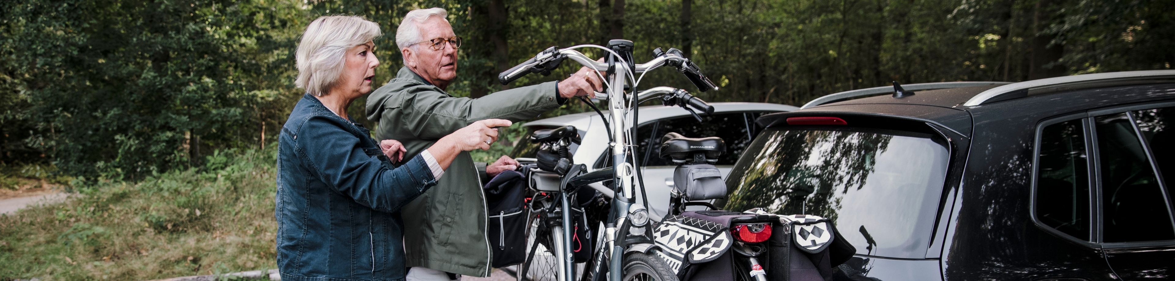 Man en vrouw zetten 2 fietsen op de auto om op fietsvakantie te gaan.