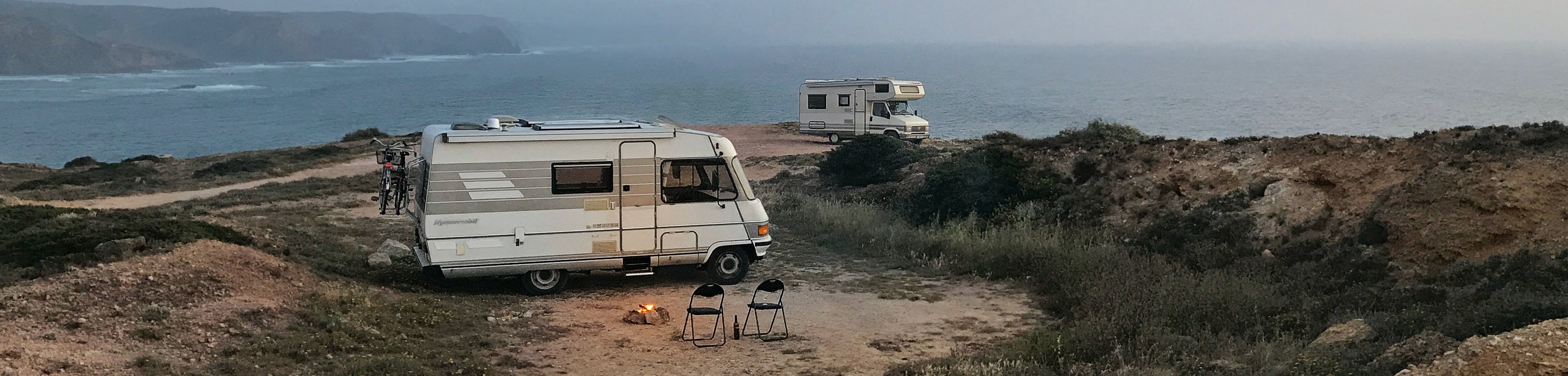Twee campers op een camping met uitzicht op zee