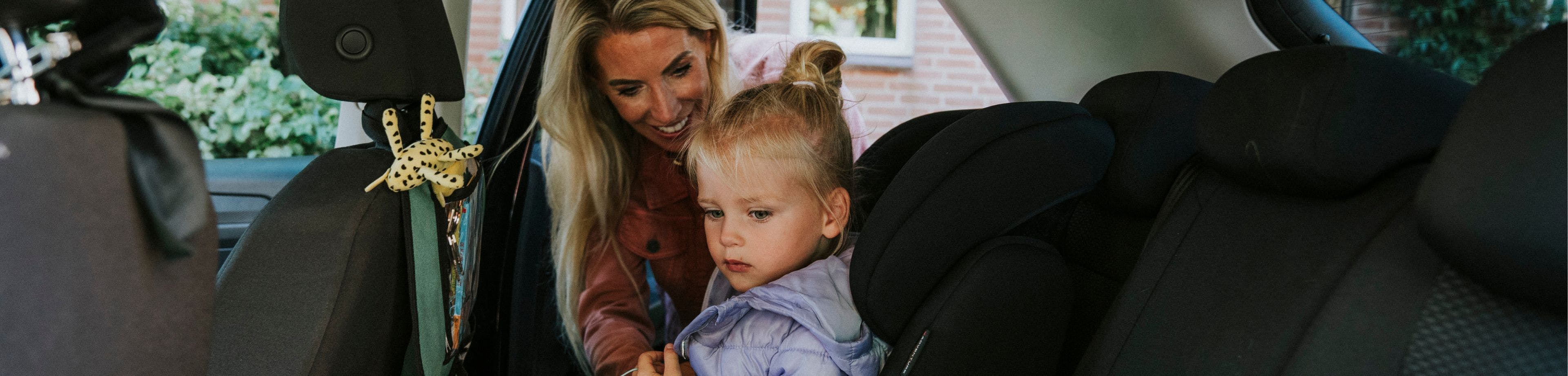 Vrouw zet een kind in een kinderstoel op de achterbank van een auto