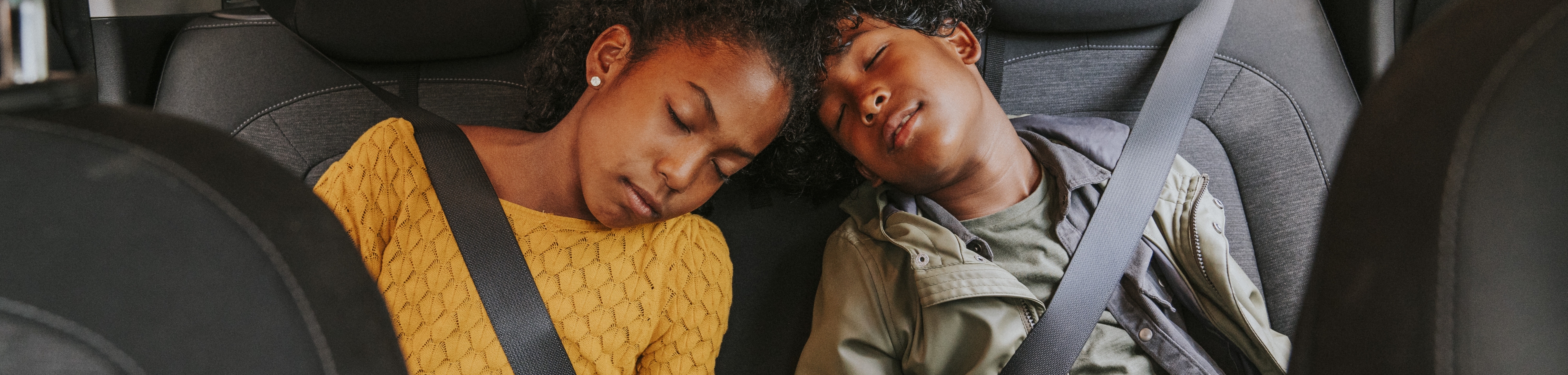2 kinderen zitten slapend op de achterbank van een auto