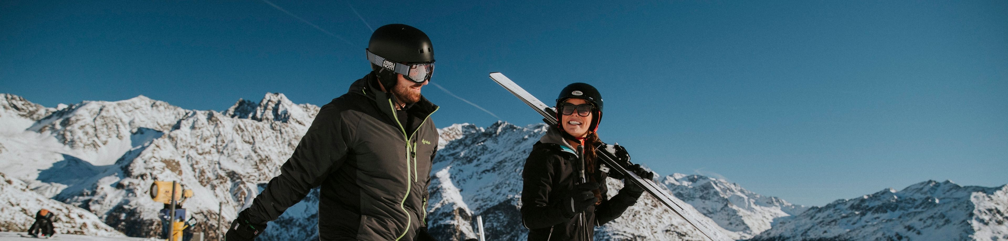 Man en vrouw lachend op de piste. Goed voorbereid op wintersport.