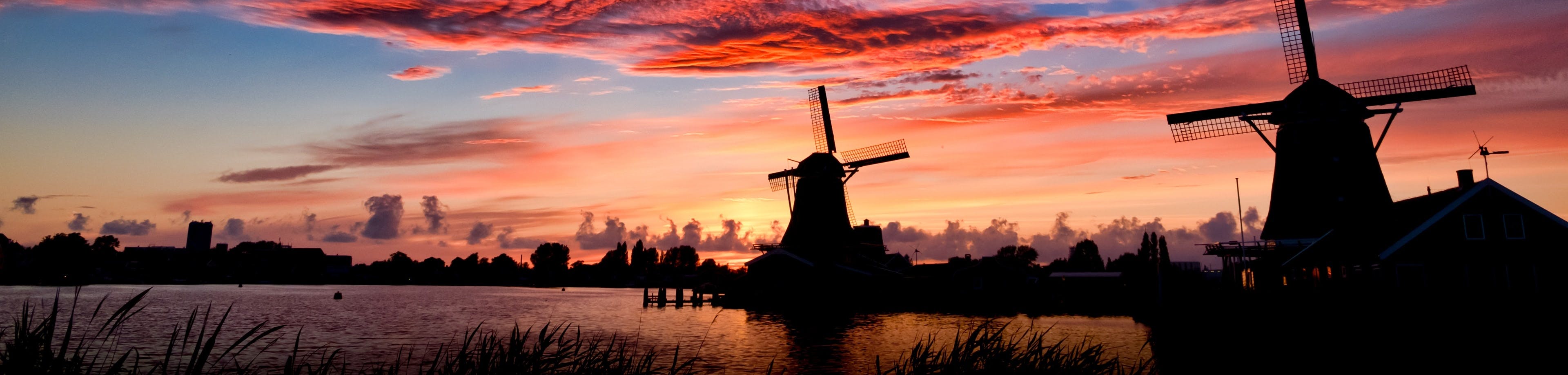 Een Hollands landschap met twee molens, in het avondrood