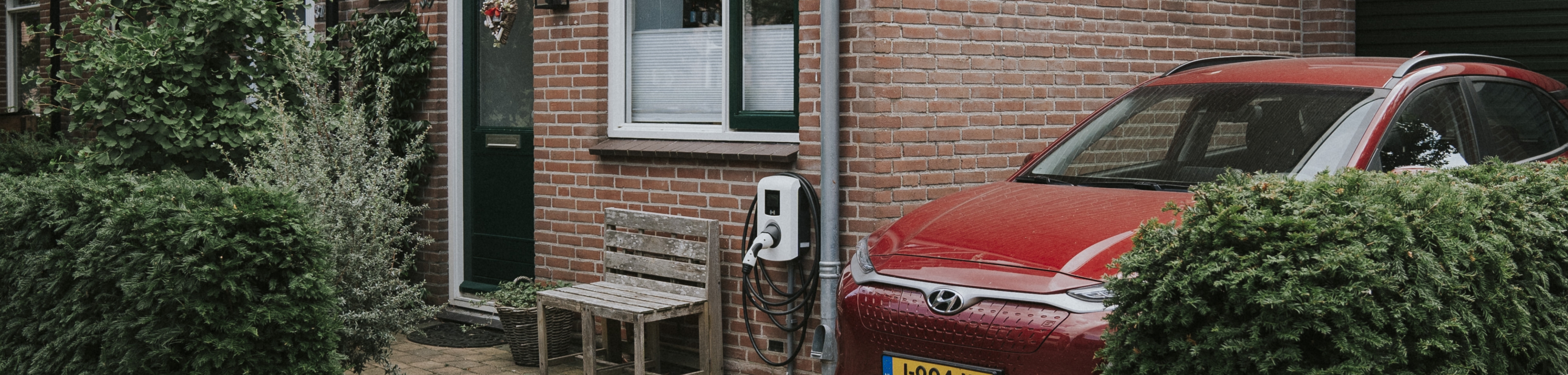 Een auto staat op de oprit geparkeerd, naast een huis