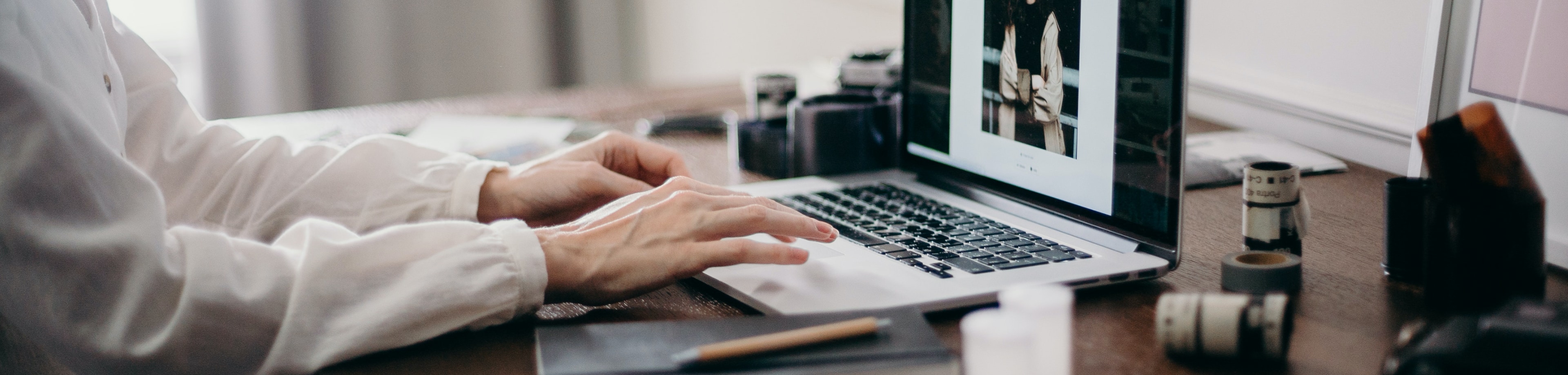 Iemand die thuis achter zijn bureau op een laptop aan het werken is