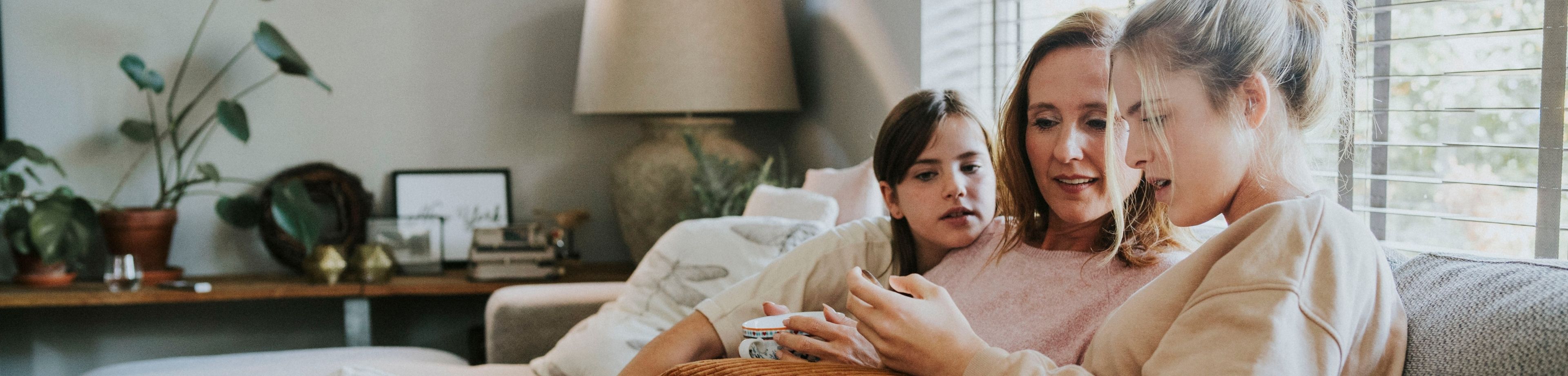 Moeder zit met haar dochters achter de laptop. Waar moet je op letten als je zorgverzekeringen gaat vergelijken?