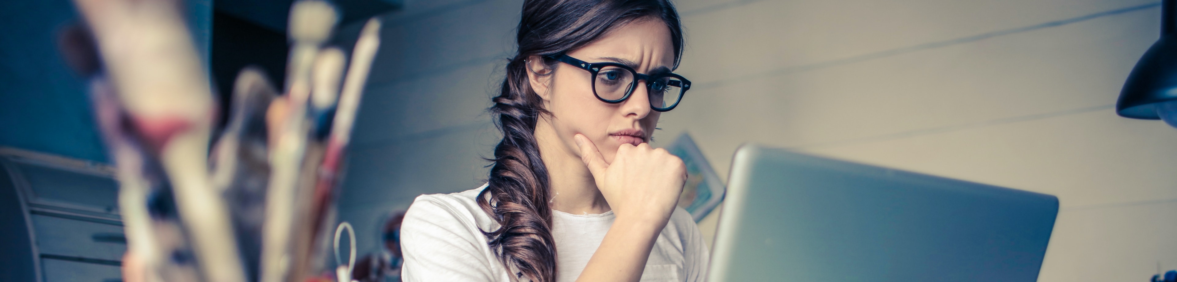 Een vrouw die achter haar laptop zit en met haar ogen fronst