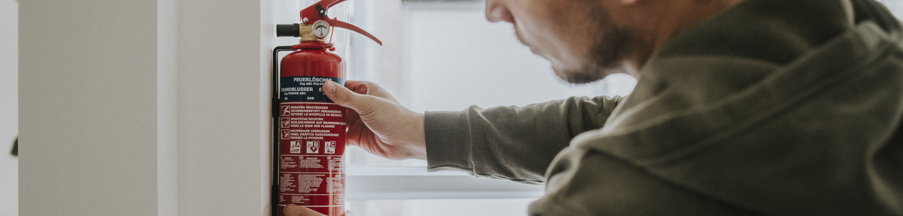 Man hangt brandblusser aan de muur
