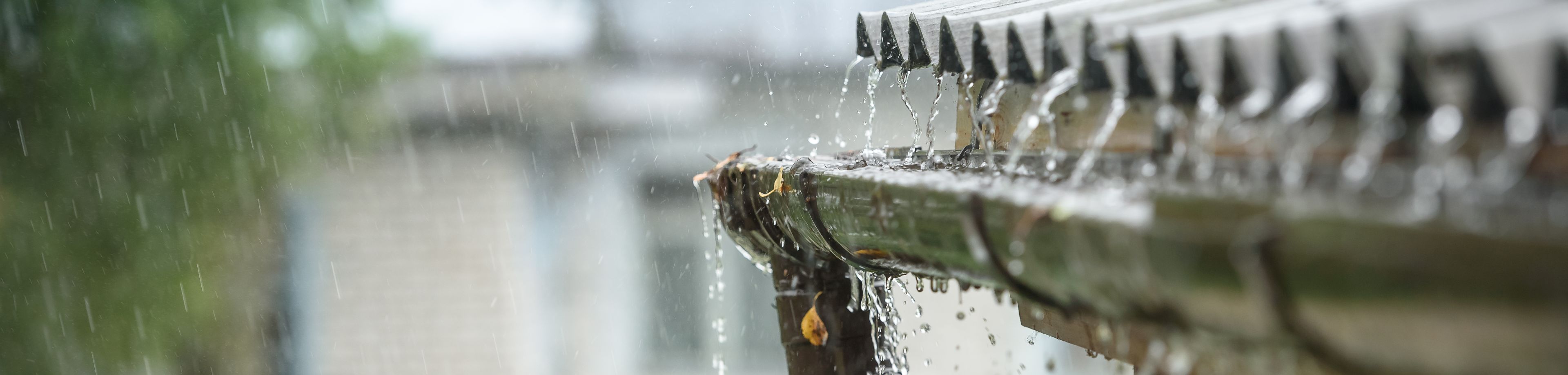 Een dakgoot overstroomt door de grote hoeveelheid regenwater die er vanaf het dak in terechtkomt.