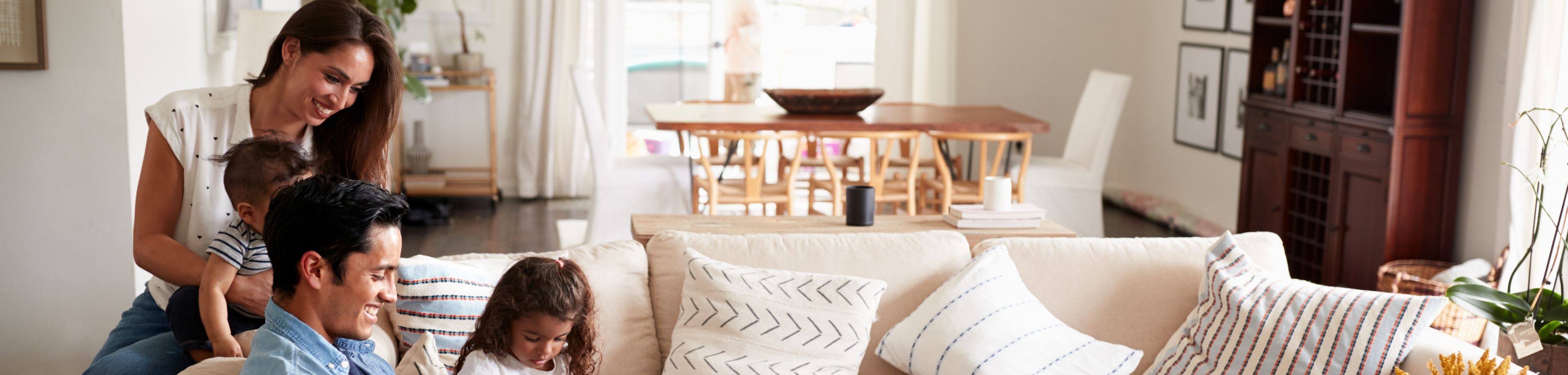 Man, vrouw en 2 kindjes zitten in een gezellig huis op de bank en kijken naar de iPad