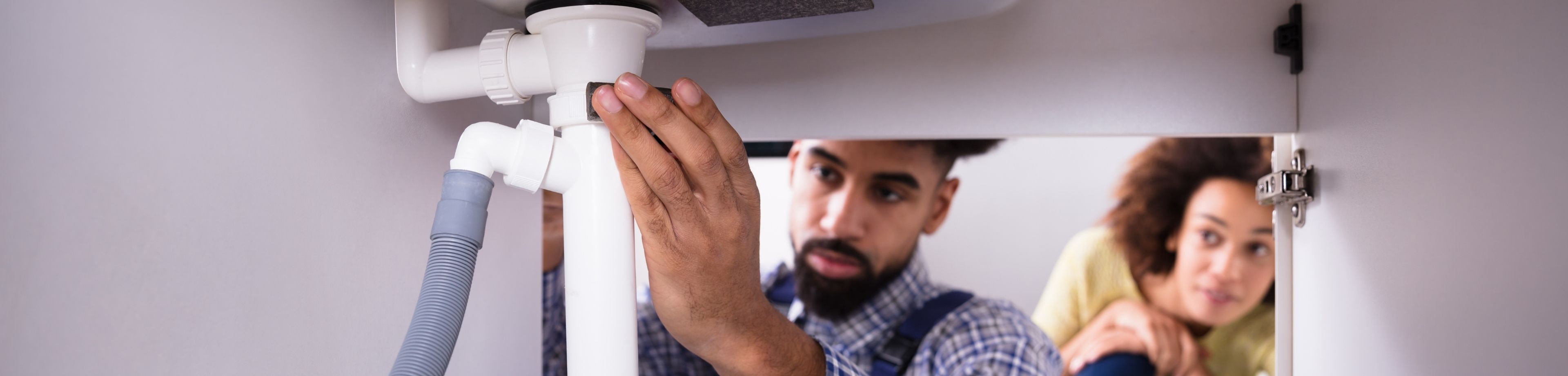 Loodgieter controleert de afvoerbuis van een gootsteen