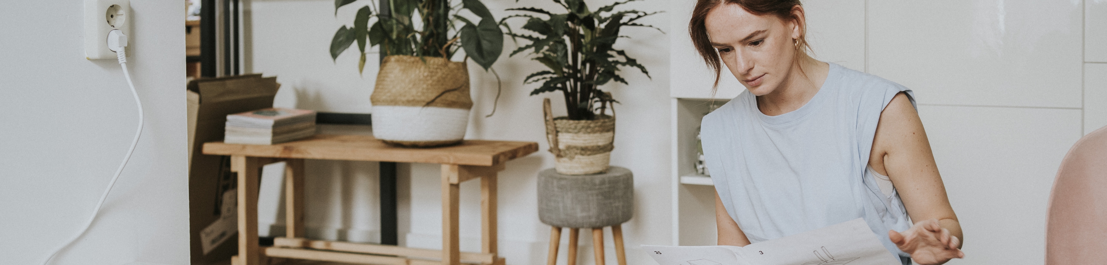 Een vrouw zit op de vloer en leest een gebruiksaanwijzing om iets in elkaar te zetten.