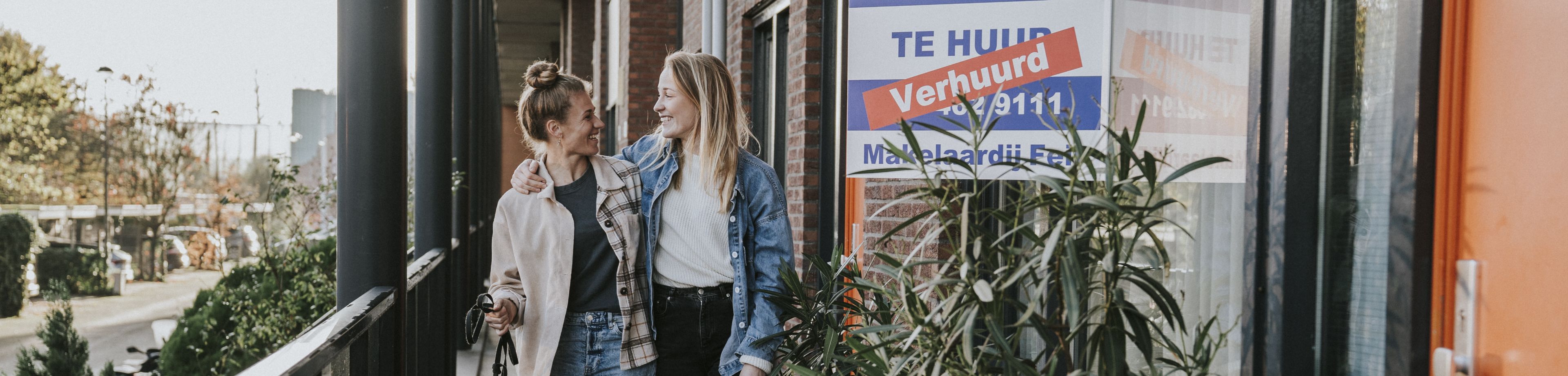 2 vrouwen staan samen met hun hond voor hun nieuwe huurappartement.
