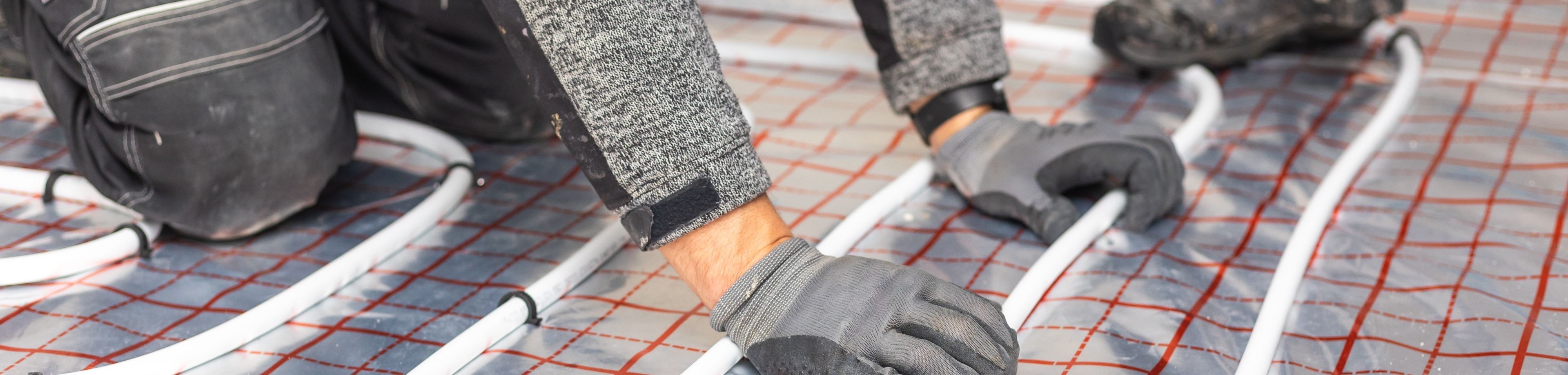 Een foto van iemand die een vloerverwarming aan het installeren is.