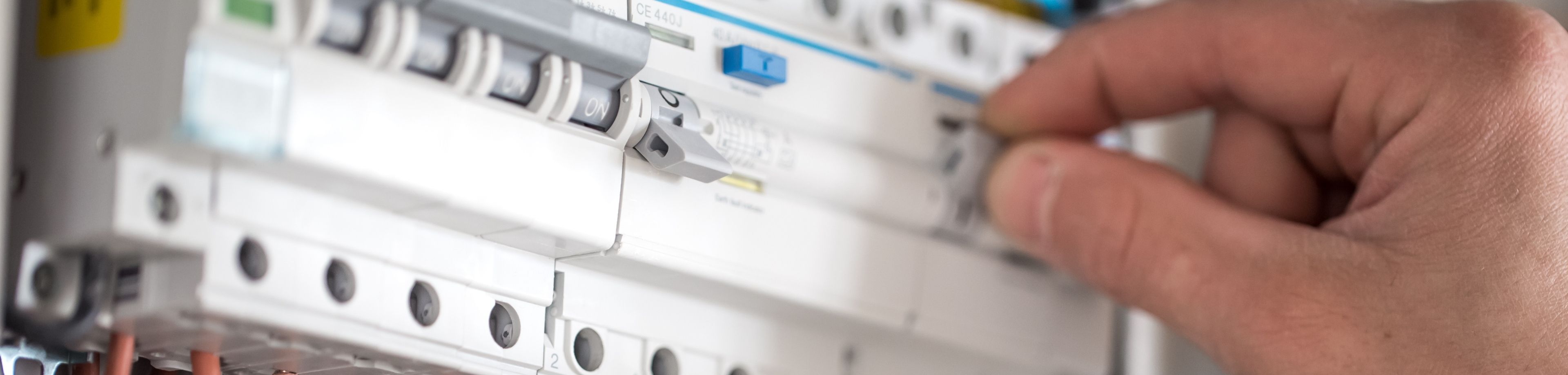 Detailfoto van de meterkast; te zien is dat iemand de hoofdschakelaar om zet.